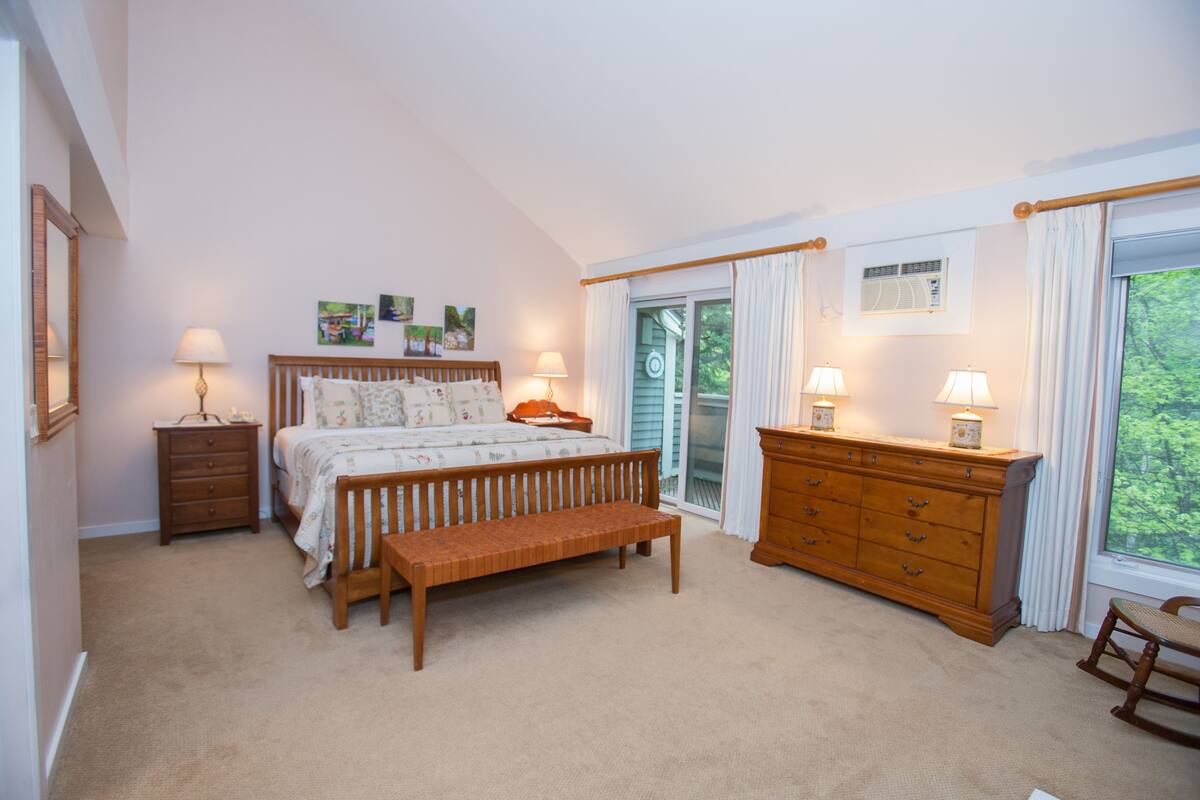 A bedroom with a bed, wooden bench, dresser, and two lamps.