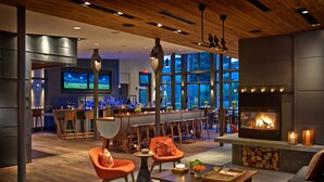 Una sala de estar moderna con chimenea, zona de estar y un bar/salón de paradas al fondo.