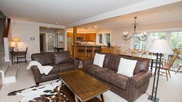 A spacious living room with two brown leather sofas, a wooden coffee table, and a large rug.