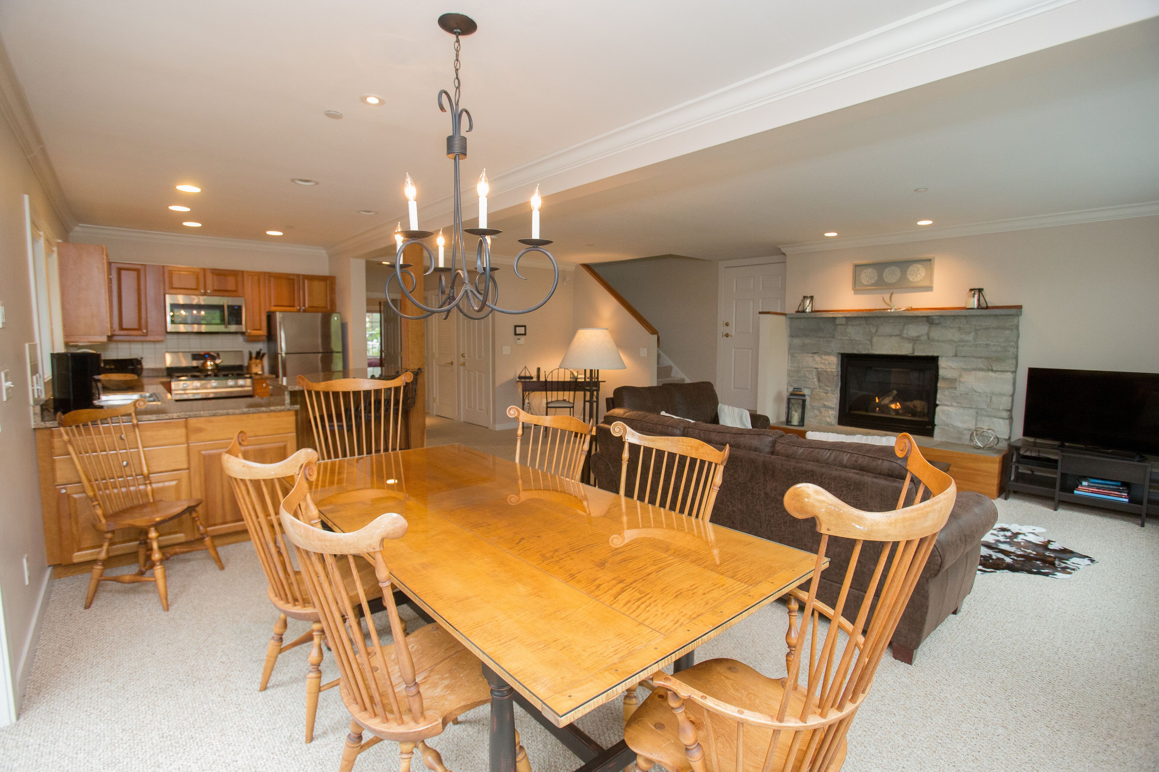 A spacious living area with a wooden dining table, chairs, a sofa, and a fireplace.