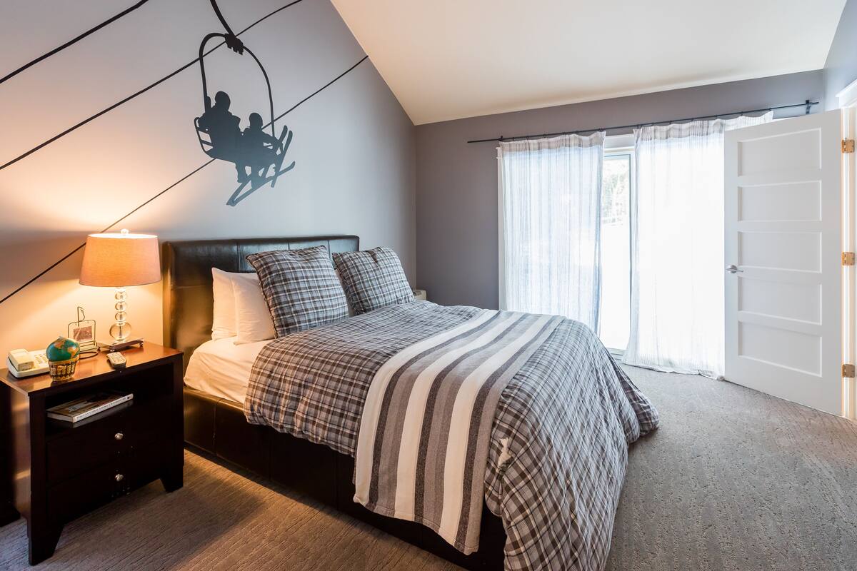 A neatly made bed with a striped blanket, a bedside lamp, and a nightstand with a globe and books.