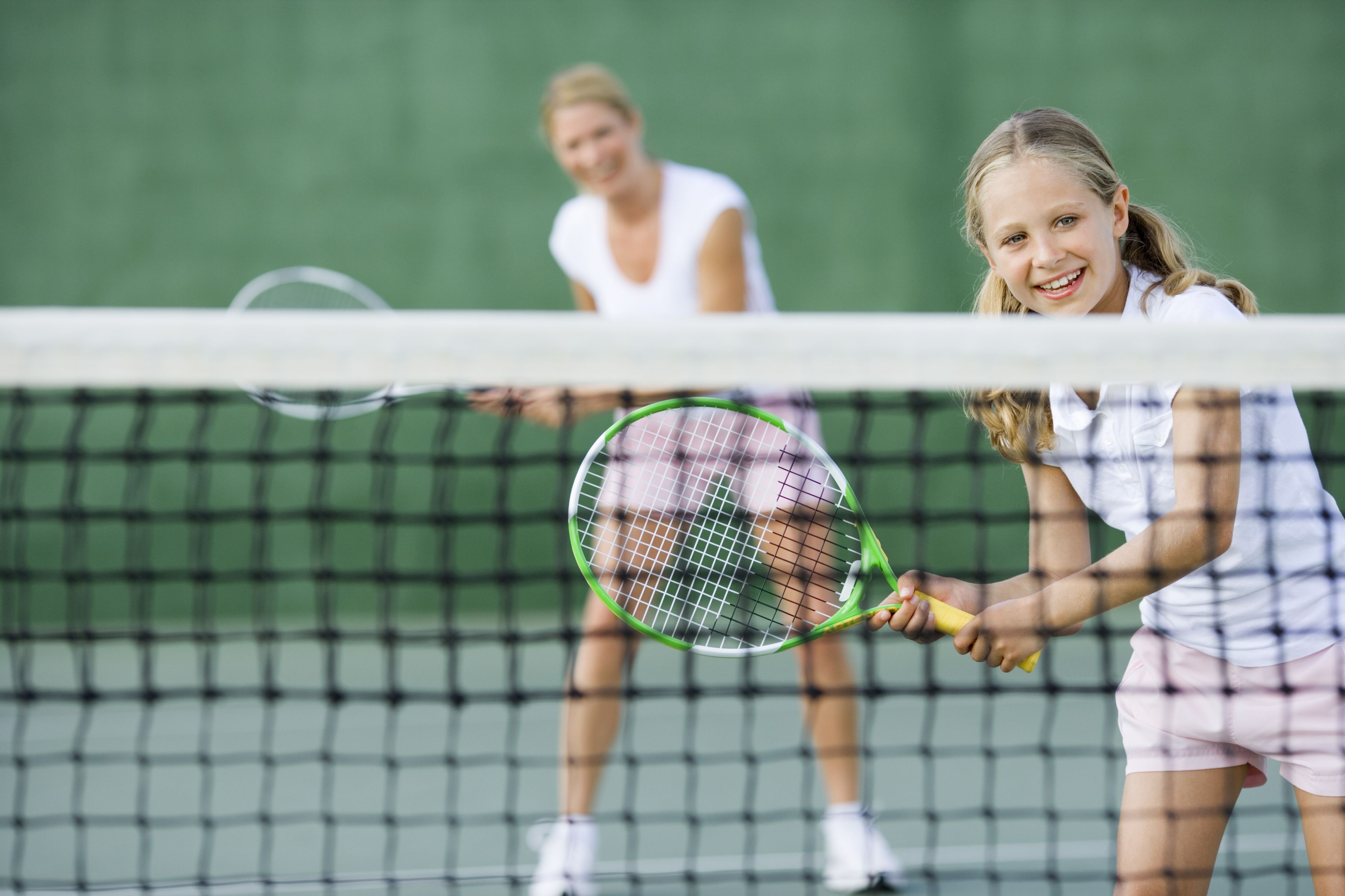 A tennis court with a net in the foreground and two players in the background.
