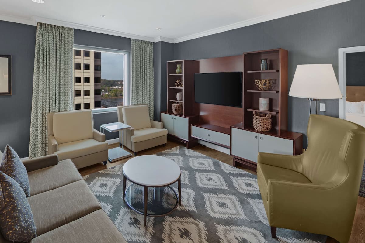A modern living room with a sofa, armchair, TV, and entertainment unit.