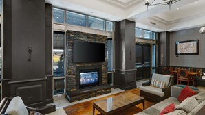 A modern living room with a stone fireplace, comfortable seating, and a large flat-screen TV mounted above the fireplace.