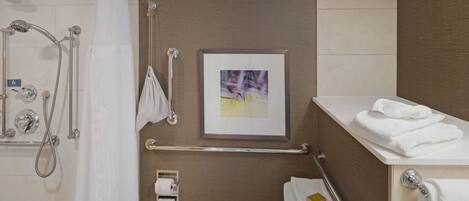 A bathroom with a shower, toilet, and a framed picture on the wall.