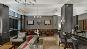 A modern hotel lobby with a seating area, a bar, and a dining space.
