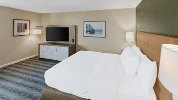 A hotel room with a bed, a television, a desk, and a lamp.