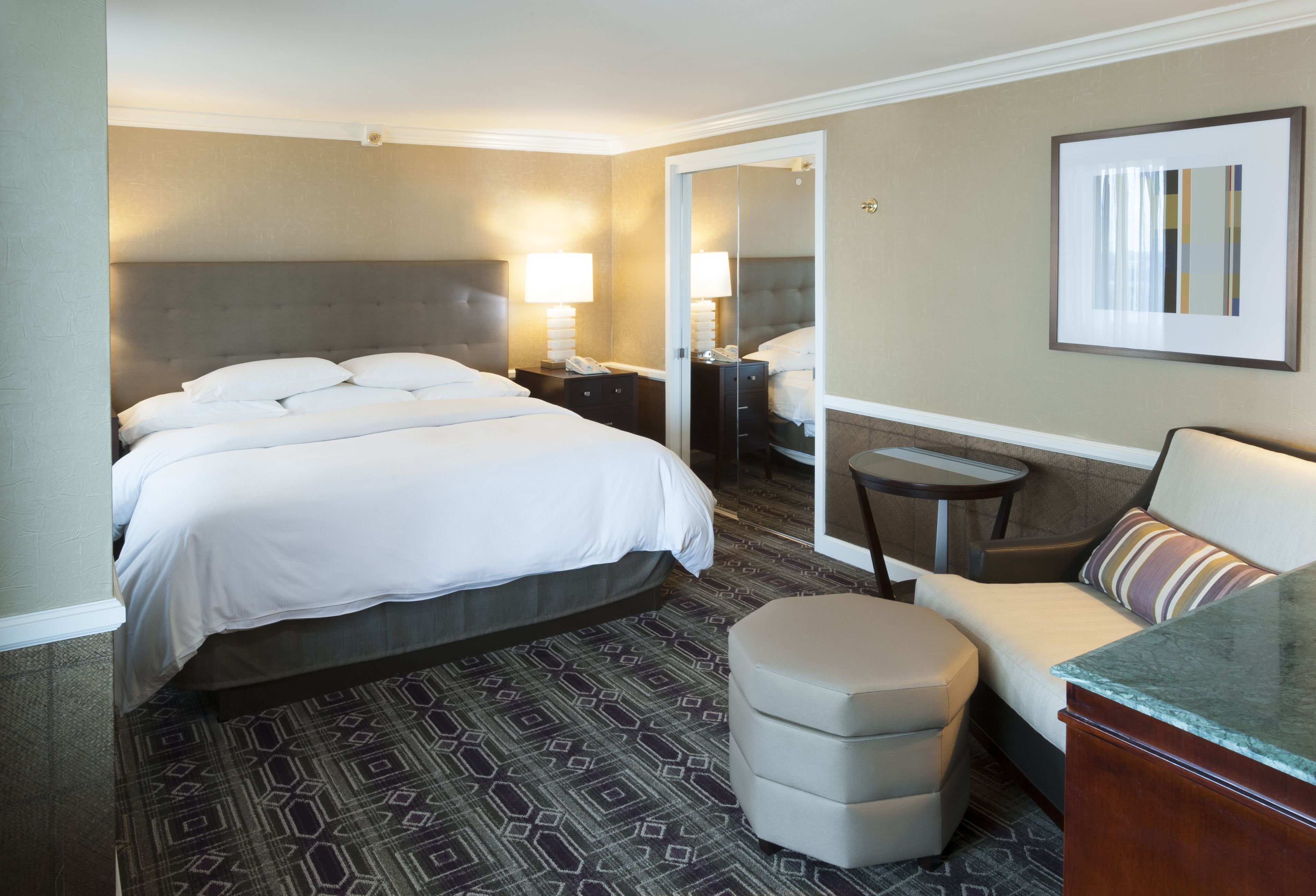 Een hotelkamer met een groot bed, een bank, een tafeltje en een spiegel.