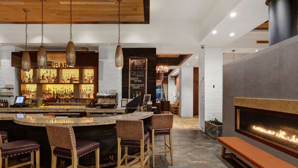 A bar area with a counter, stools, and a fireplace.