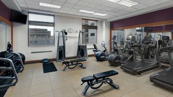 Een sportschool met diverse fitnessapparaten, waaronder loopbanden, elliptische trainers en krachtapparaten.