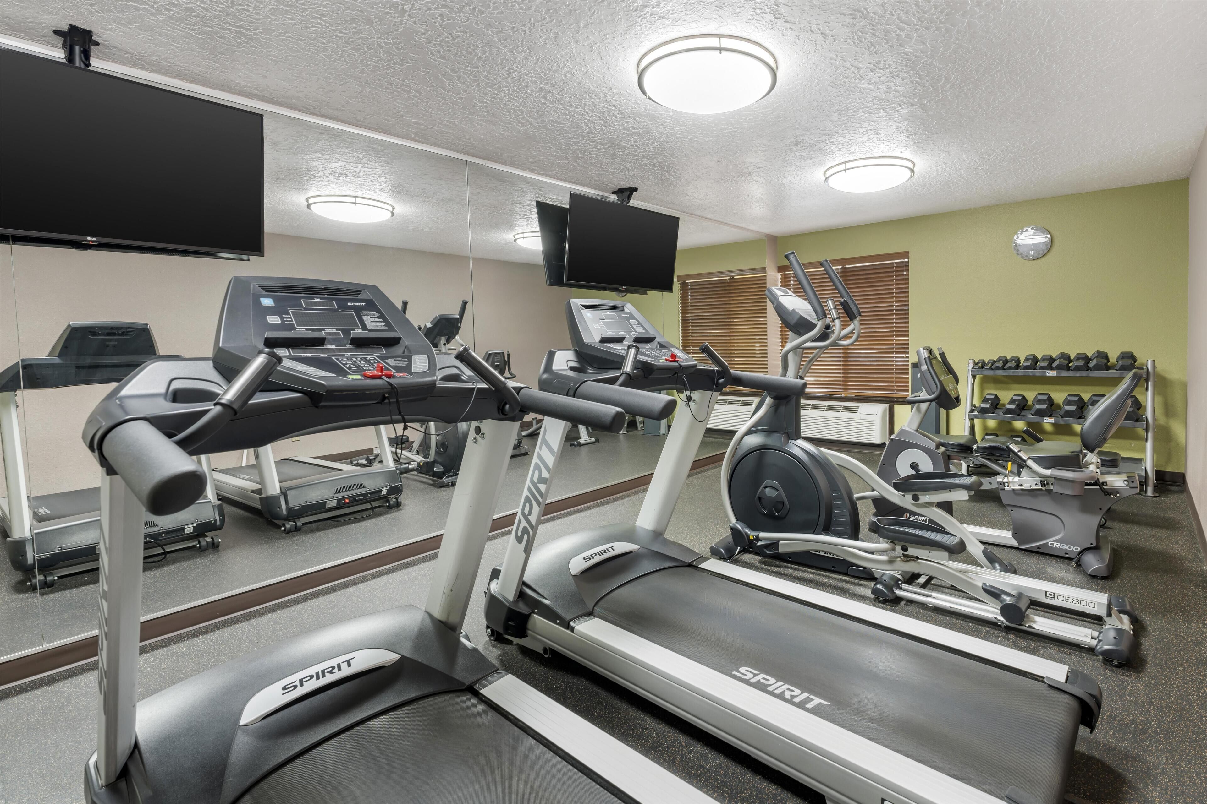 Une salle de sport équipée de tapis de course, d’un vélo d’appartement et d’un banc de musculation.