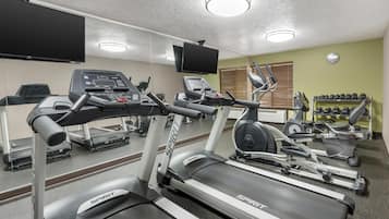 Une salle de sport équipée de tapis de course, d’un vélo d’appartement et d’un banc de musculation.