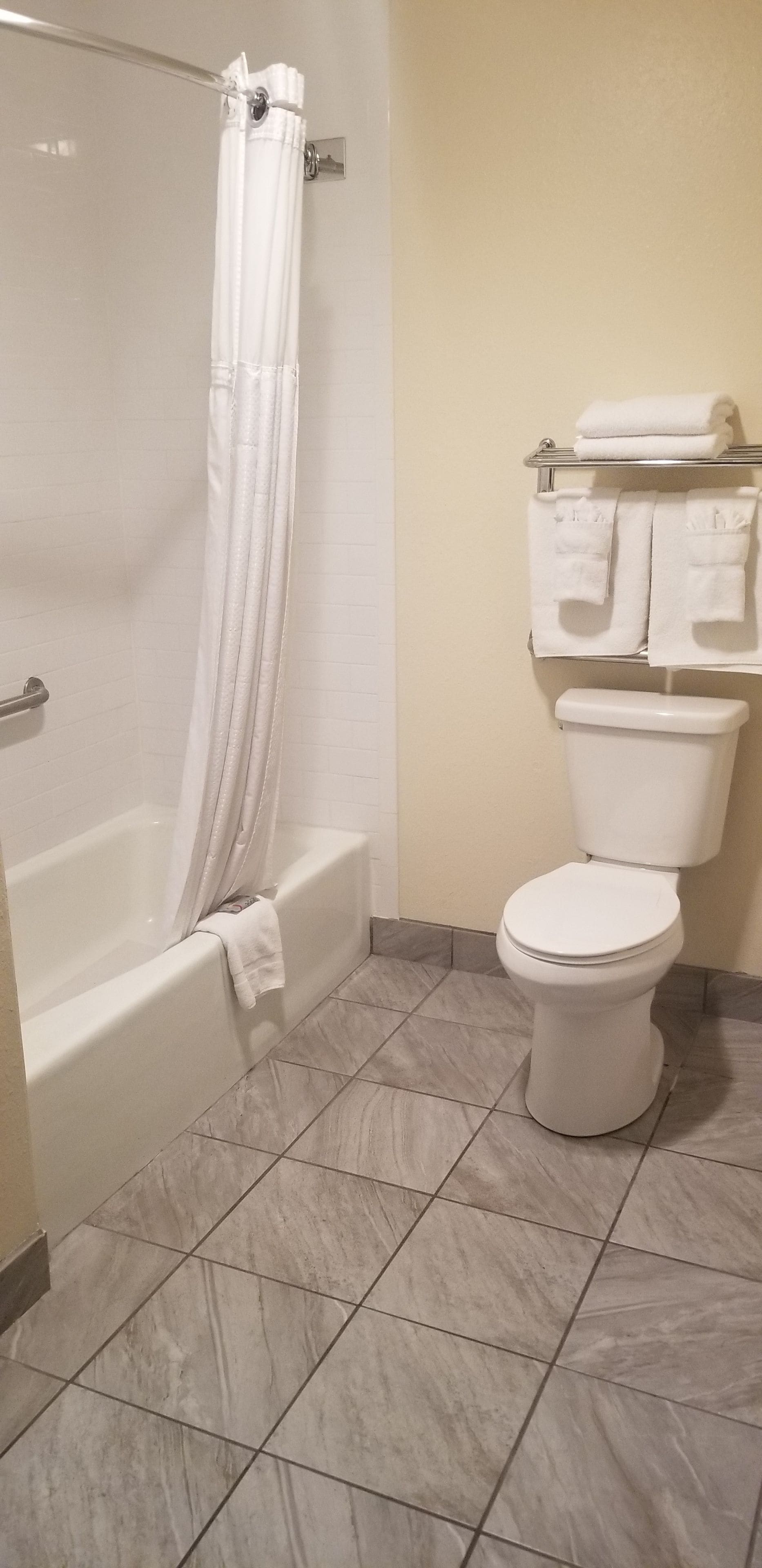 Un baño con bañera, inodoro y un perchero con toallas.