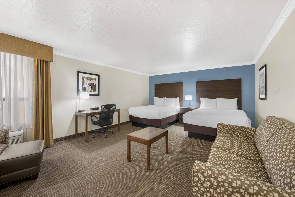 Een hotelkamer met twee bedden, een bureau, een stoel, een bank en een kleine tafel.