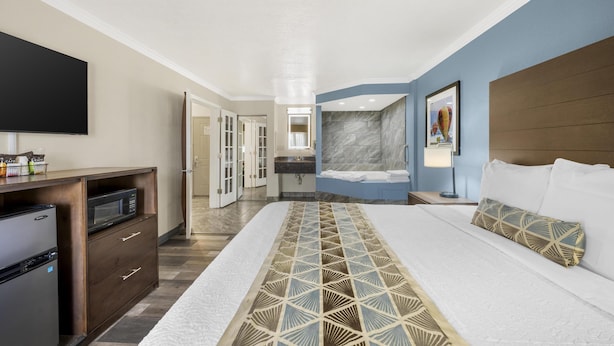 A hotel room with a bed, a TV, a microwave, and a refrigerator. - Best Western Airport Albuquerque InnSuites Hotel & Suites (Albuquerque)