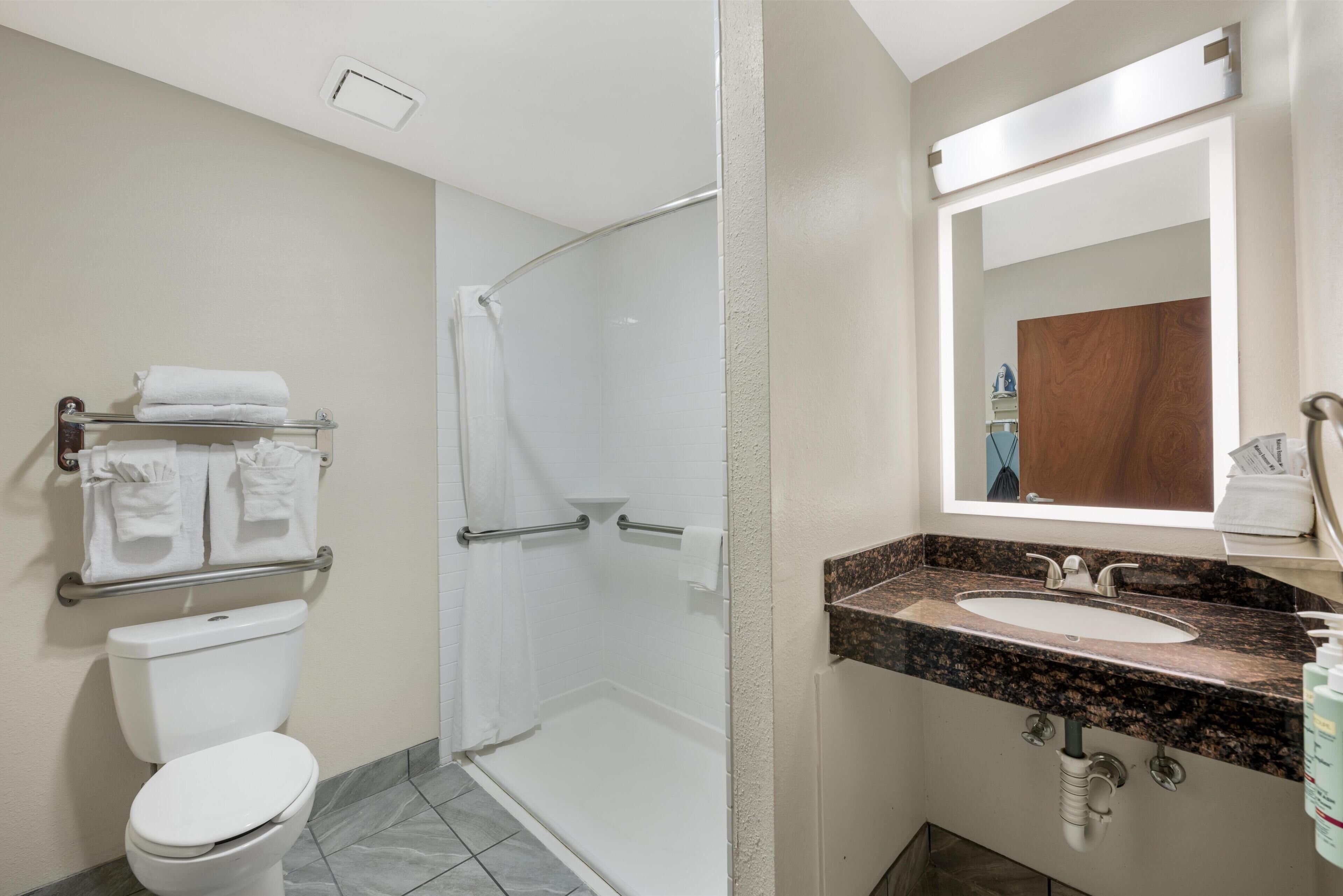 A bathroom with a toilet, shower, and sink.