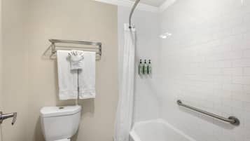 Une salle de bain avec une baignoire blanche, un rideau de douche, des toilettes et un porte-serviettes avec deux serviettes.
