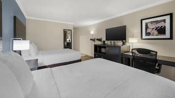A hotel room with two beds, a desk, a chair, a TV, and a framed picture on the wall.