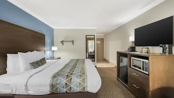 Une chambre d’hôtel avec un grand lit, un téléviseur à écran plat, un four à micro-ondes et un bureau avec des tiroirs.