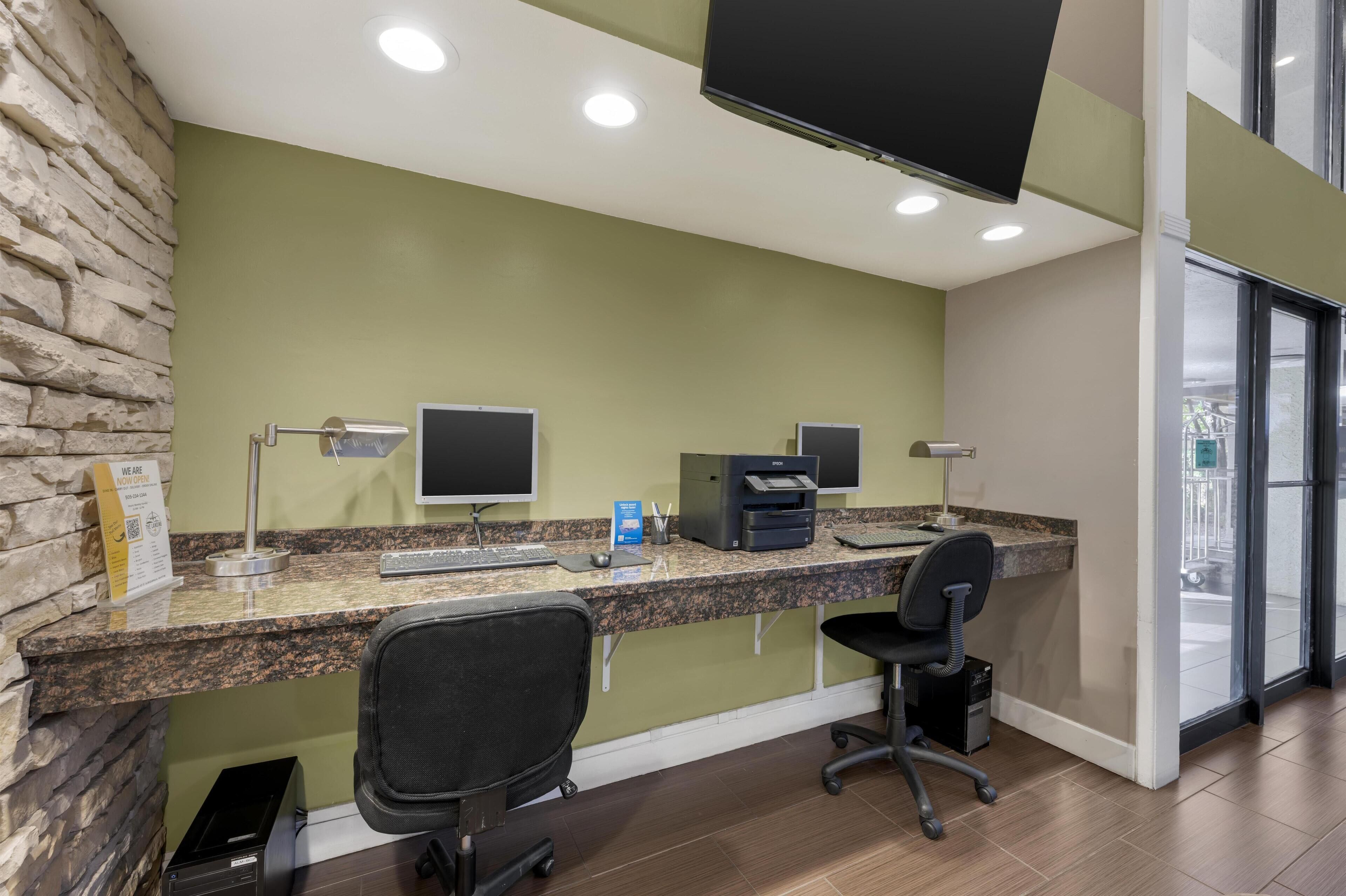 A reception desk with a stone accent wall, a flat-screen monitor, a printer, and a computer.