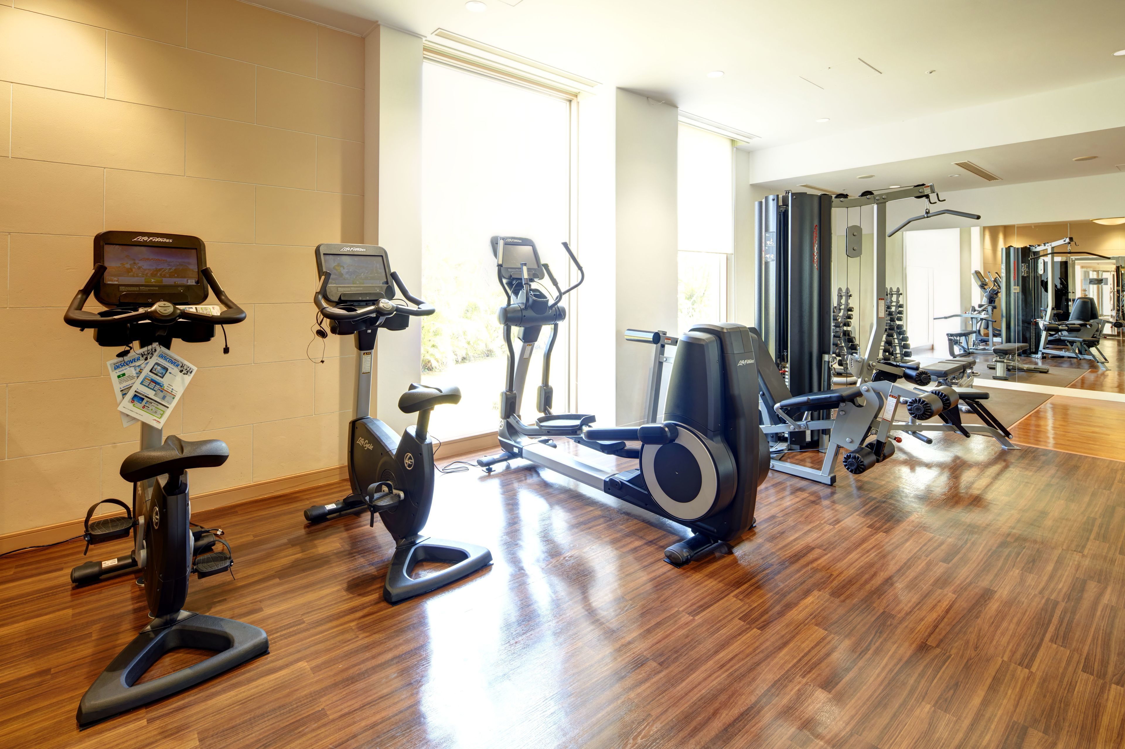 Une salle de sport équipée de divers appareils d’exercice, notamment des tapis de course, des vélos d’appartement et des appareils de musculation.
