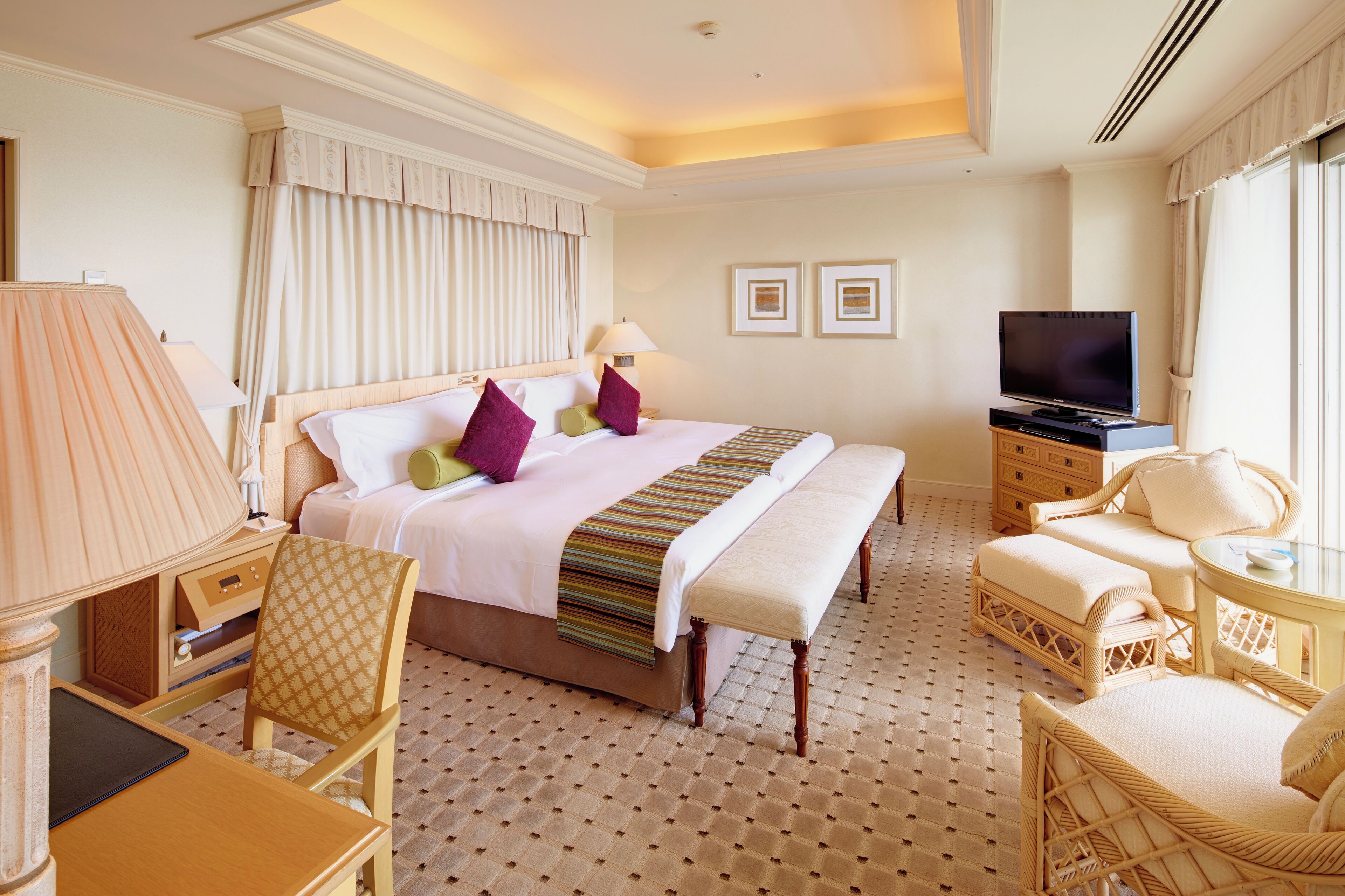 A hotel room with a large bed, a TV, a desk, and a chair.
