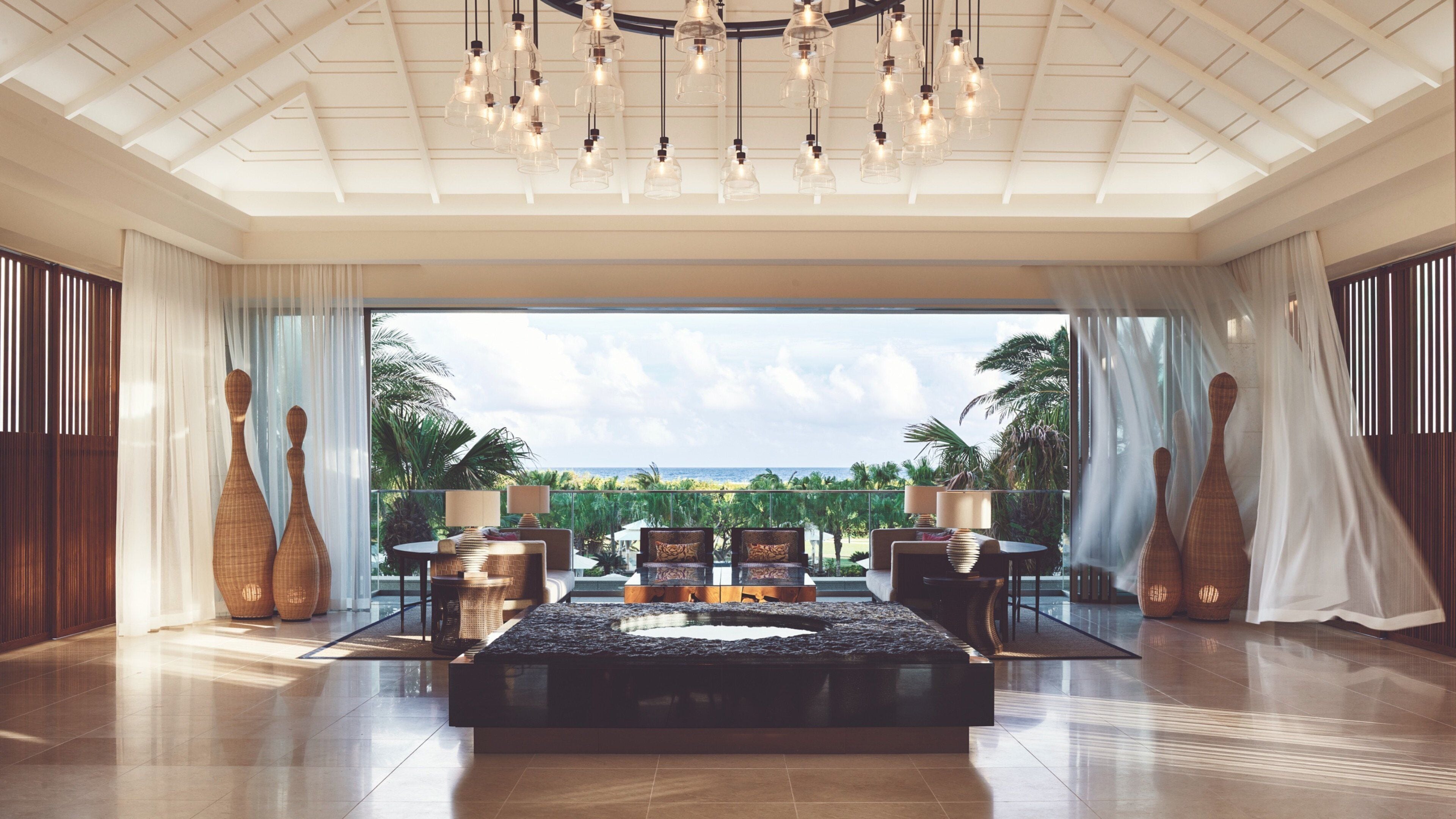 Una habitación amplia con una cama grande, un candelabro y vistas al océano.