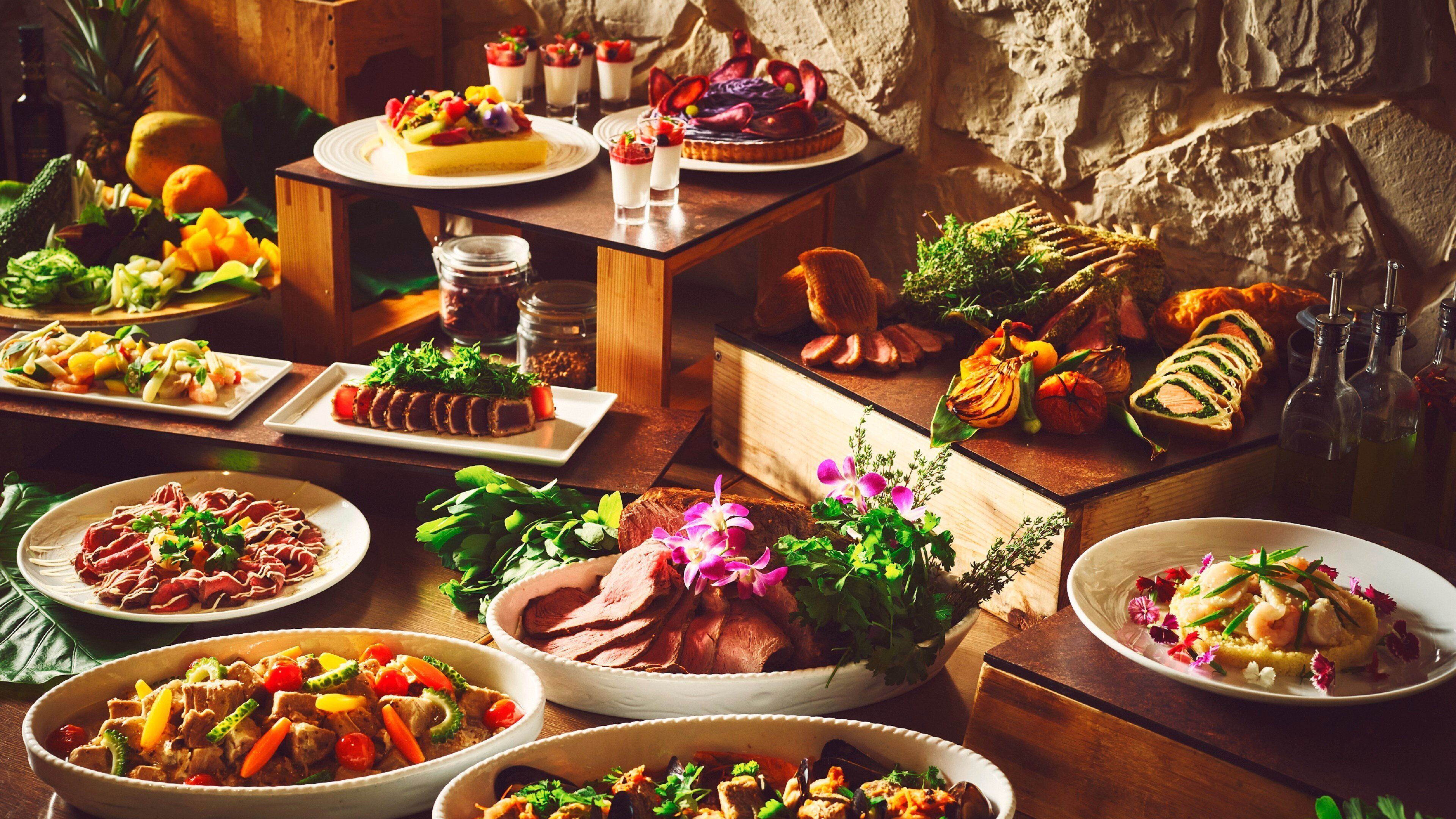 Una variedad de platos sobre una mesa de madera, incluyendo un gran asado, ensaladas y postres.