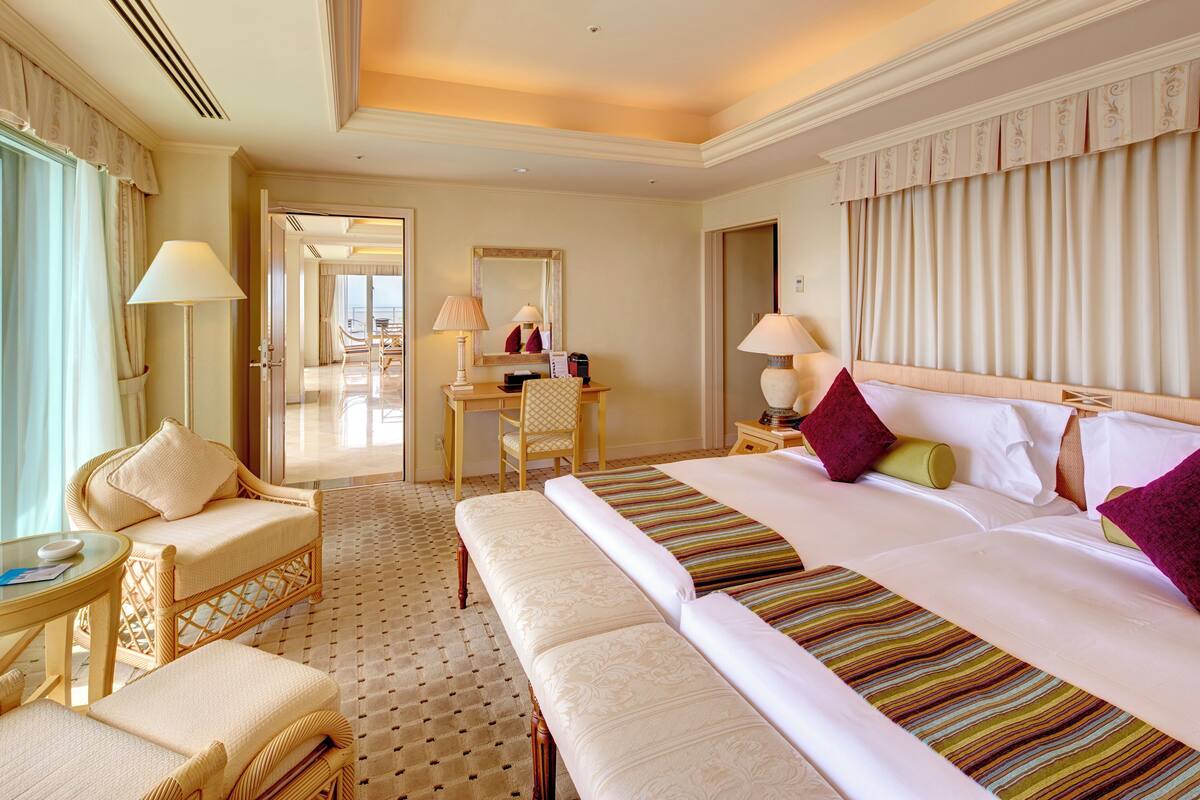 Une chambre d’hôtel avec un grand lit, un bureau avec une chaise, un canapé et une petite table.