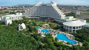 Un grand hôtel composé de plusieurs bâtiments, doté d’une piscine centrale et entouré de verdure.