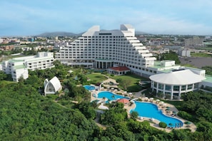 Un gran hotel con varias edificaciones, una piscina central y zonas verdes circundantes.