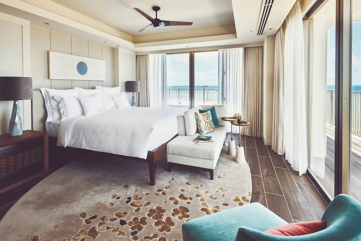 Une chambre spacieuse avec un grand lit, un coin salon et un balcon offrant une vue agréable.