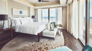 A spacious bedroom with a large bed, a seating area, and a balcony with a view.