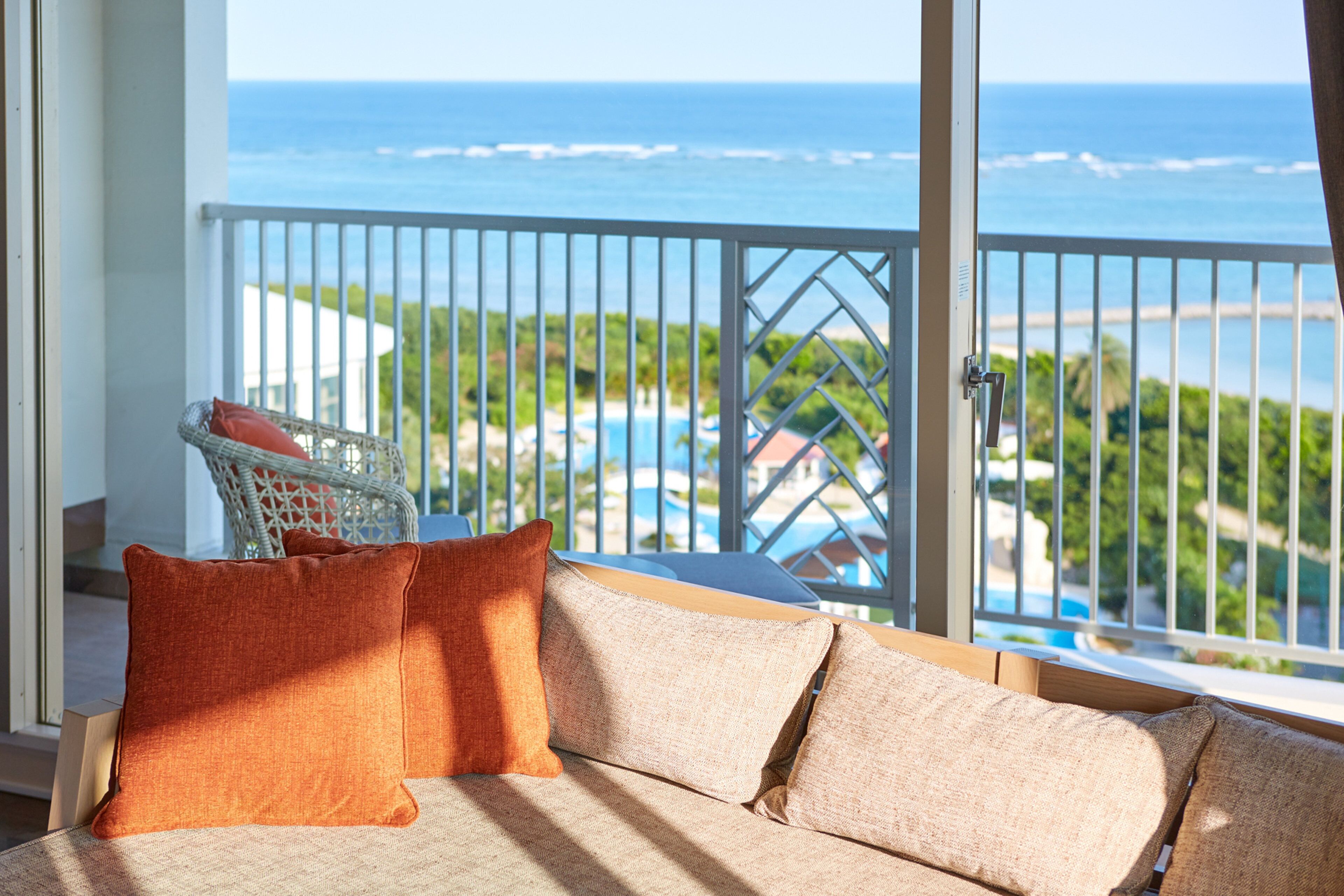 A balcony with a view of the ocean and a pool.