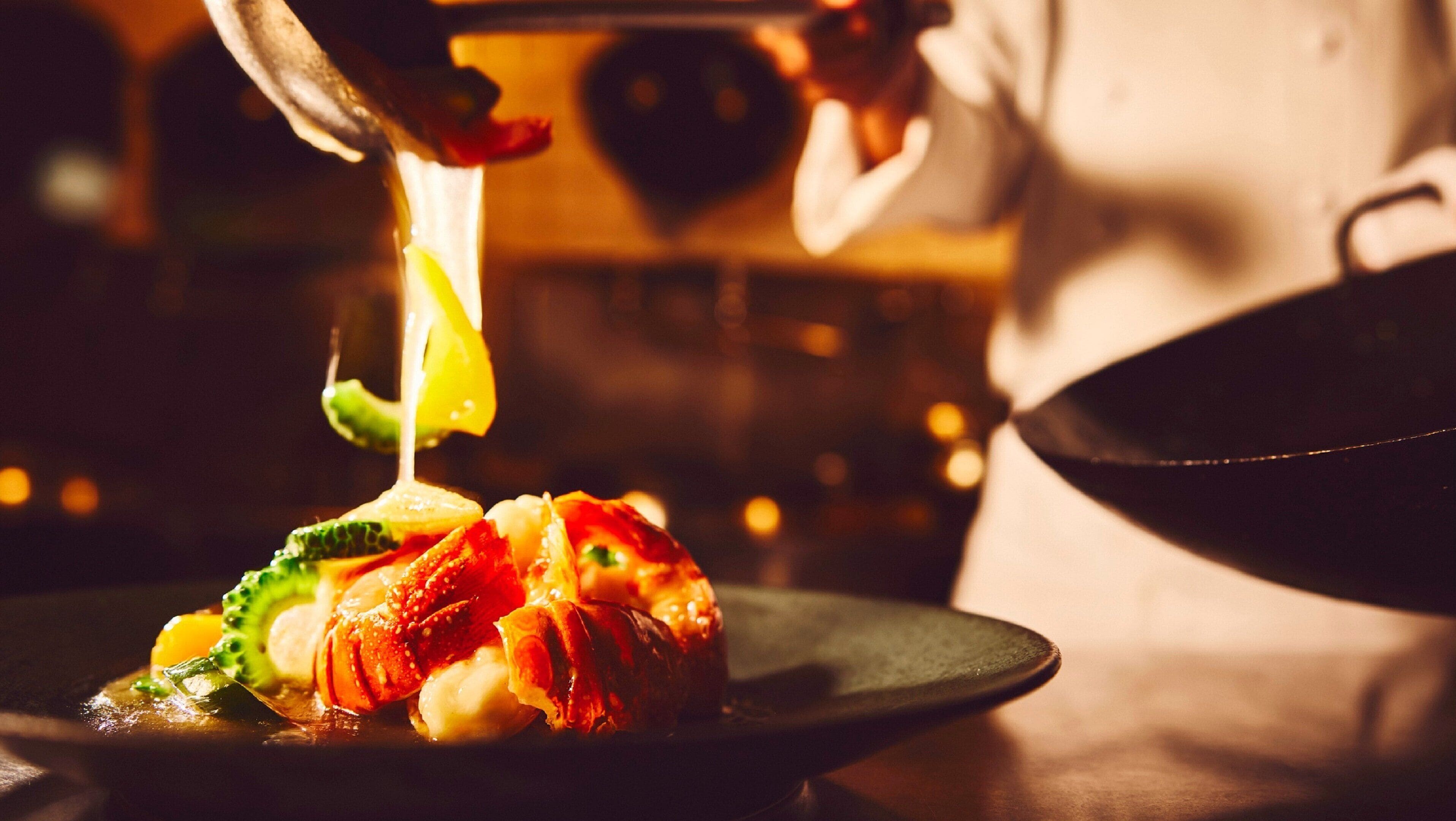 Un chef preparando un plato con diversos ingredientes, entre ellos verduras y posiblemente mariscos.