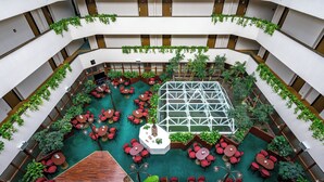 A multi-level atrium with a central glass greenhouse, surrounded by red seating areas and greenery. - Ensana Thermal Sárvár (Sarvar)