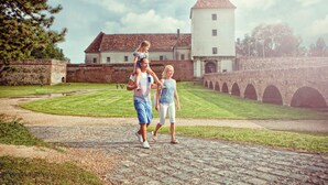 A pathway leading to a historic building with a tower and arched bridge. - Ensana Thermal Sárvár (Sarvar)
