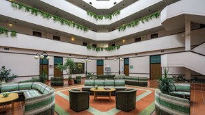 A spacious atrium with tiered seating, green plants, and a central coffee table. - Ensana Thermal Sárvár (Sarvar)