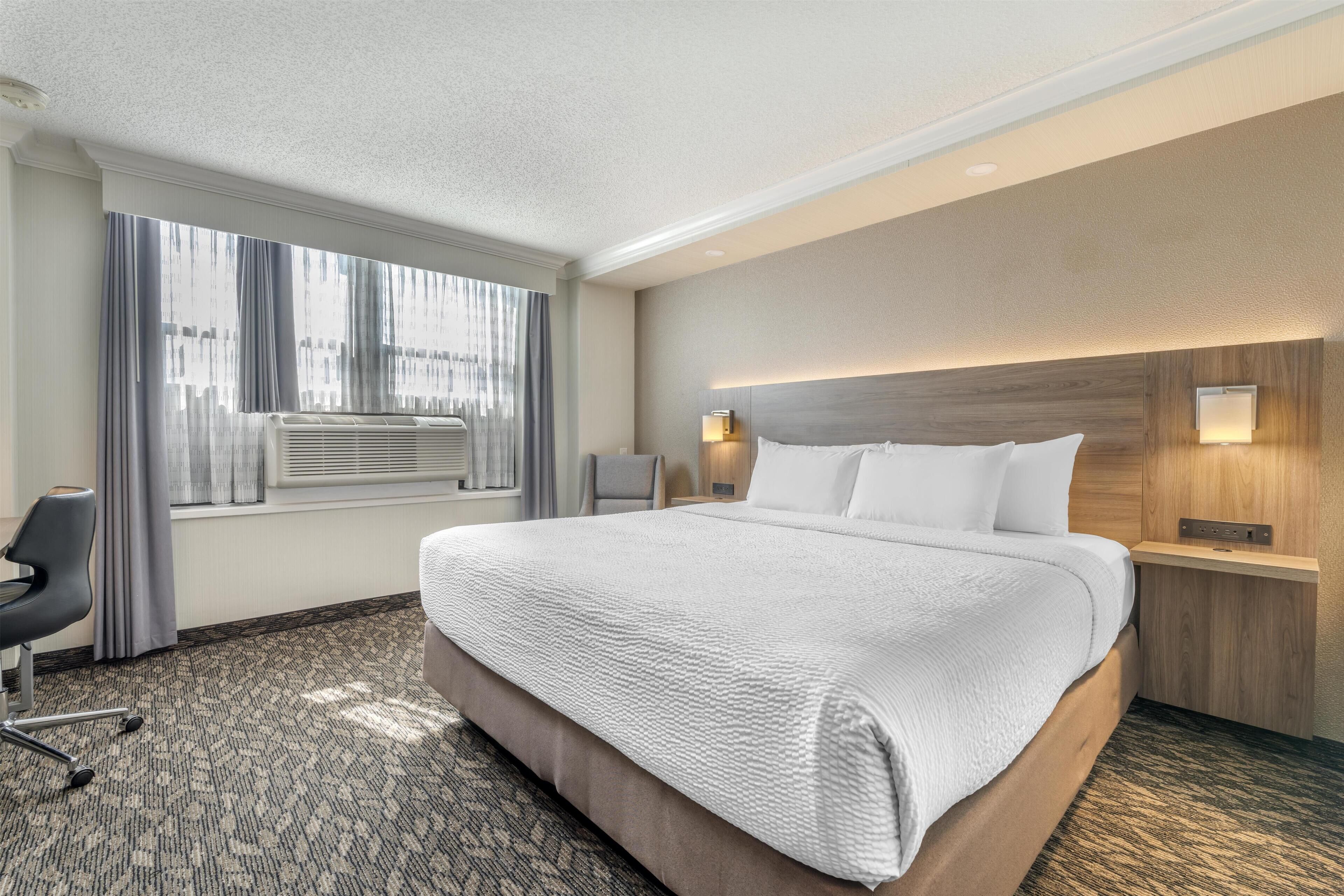 Ein Hotelzimmer mit einem großen Bett, einem Schreibtisch und einem Stuhl.