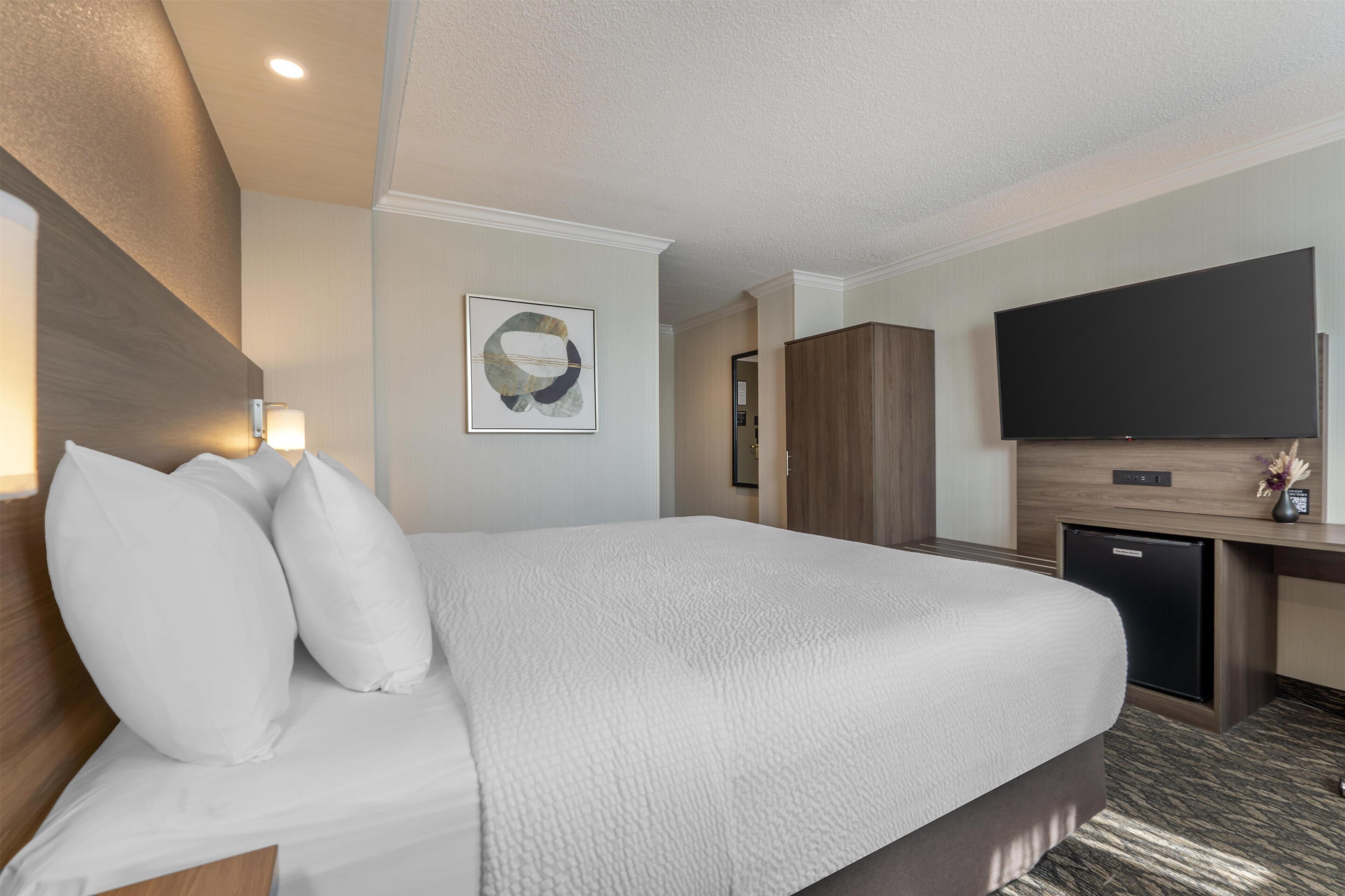 Une chambre d’hôtel avec un grand lit, un bureau doté d’une télévision à écran plat et un minibar.