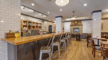 A restaurant with a bar area, high stools, and a stone fireplace.
