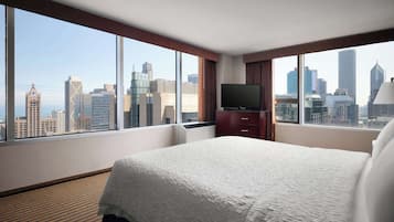 A hotel room with a large bed, a TV, and a city view.