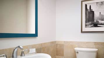 Une salle de bain avec un lavabo blanc, un miroir avec un cadre bleu, des toilettes et un tableau encadré accroché au mur.