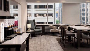 Um hall de hotel moderno com um balcão de recepção extenso, área de estar e amplas janelas com vista para a cidade.