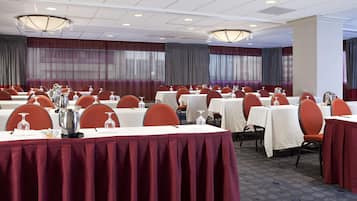 A conference room with multiple tables, each set with chairs, water pitchers, and glasses.