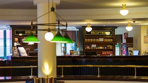 A reception area with a counter, a reception desk, and a store sign. - MAXX Hotel Jena (Jena)