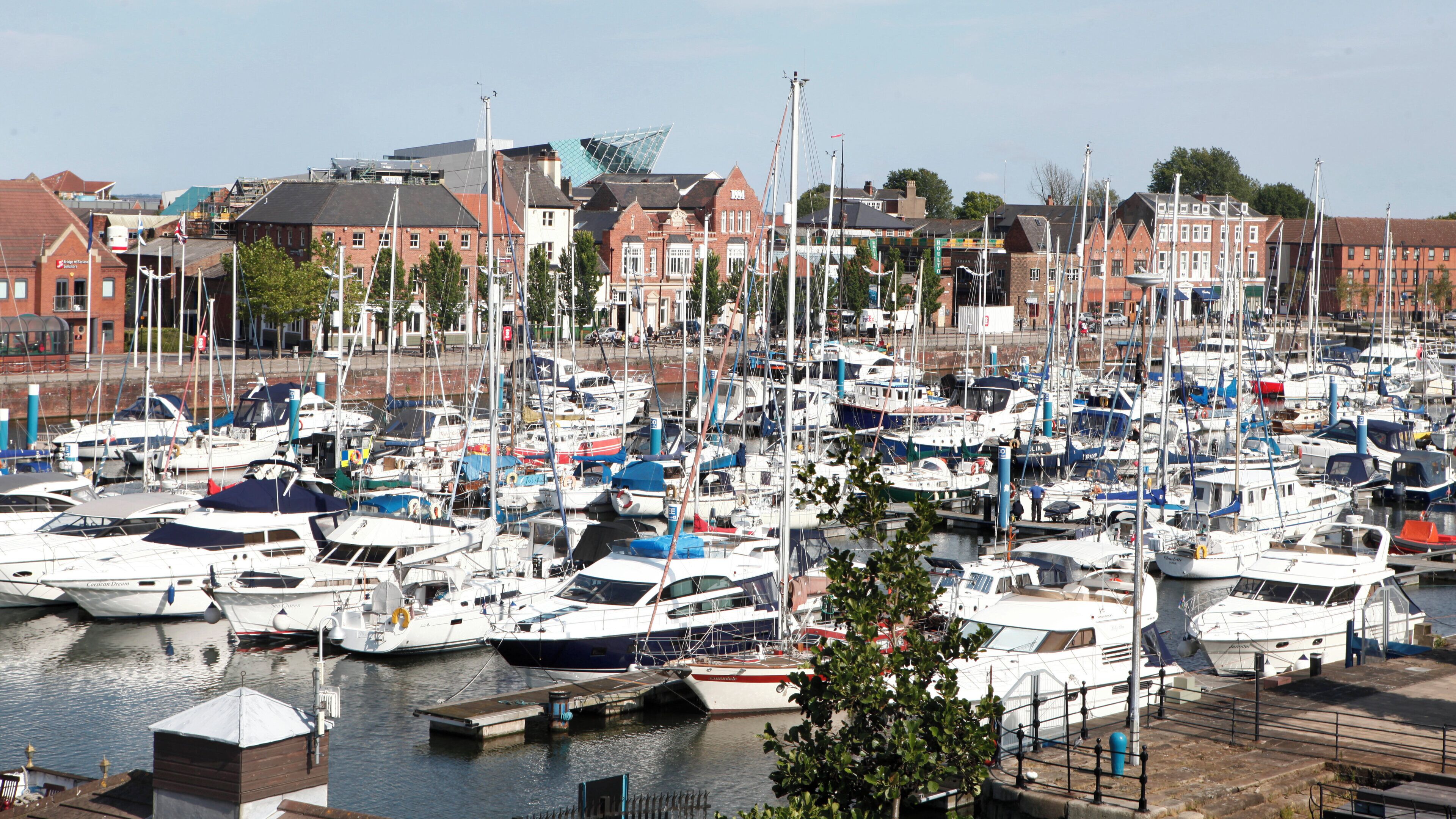 A marina with multiple boats docked, surrounded by buildings.