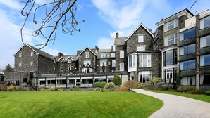 A large, multi-story building with a stone facade, a central courtyard, and a well-maintained lawn. - Macdonald Old England Hotel & Spa (Windermere)