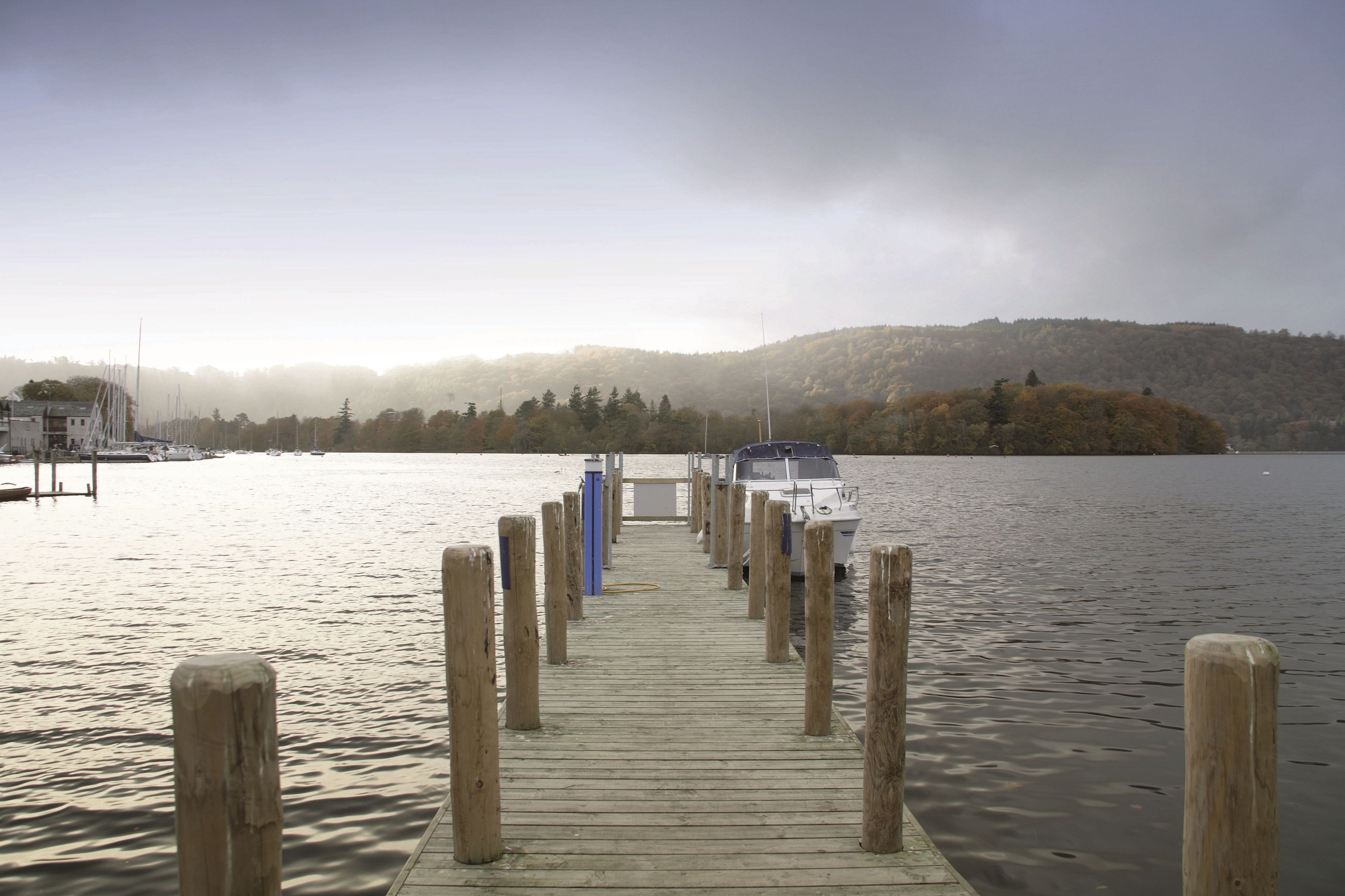 A wooden pier extending into calm water with a boat docked at the end.