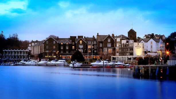 A waterfront hotel with multiple buildings, a marina with boats, and a calm evening setting. - Macdonald Old England Hotel & Spa (Windermere)